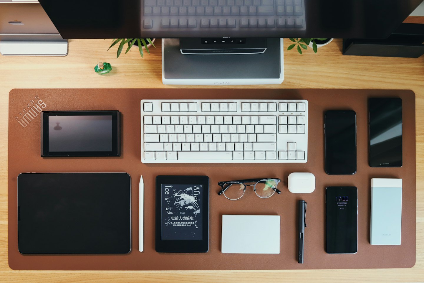Assorted tech gadgets and office supplies arranged on a leather desk.